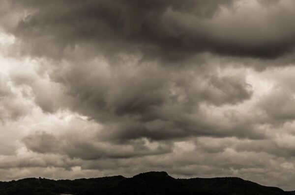 Heavy grey clouds over hilltops.